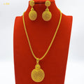 Gold necklace and earrings set on a red stand with a white background