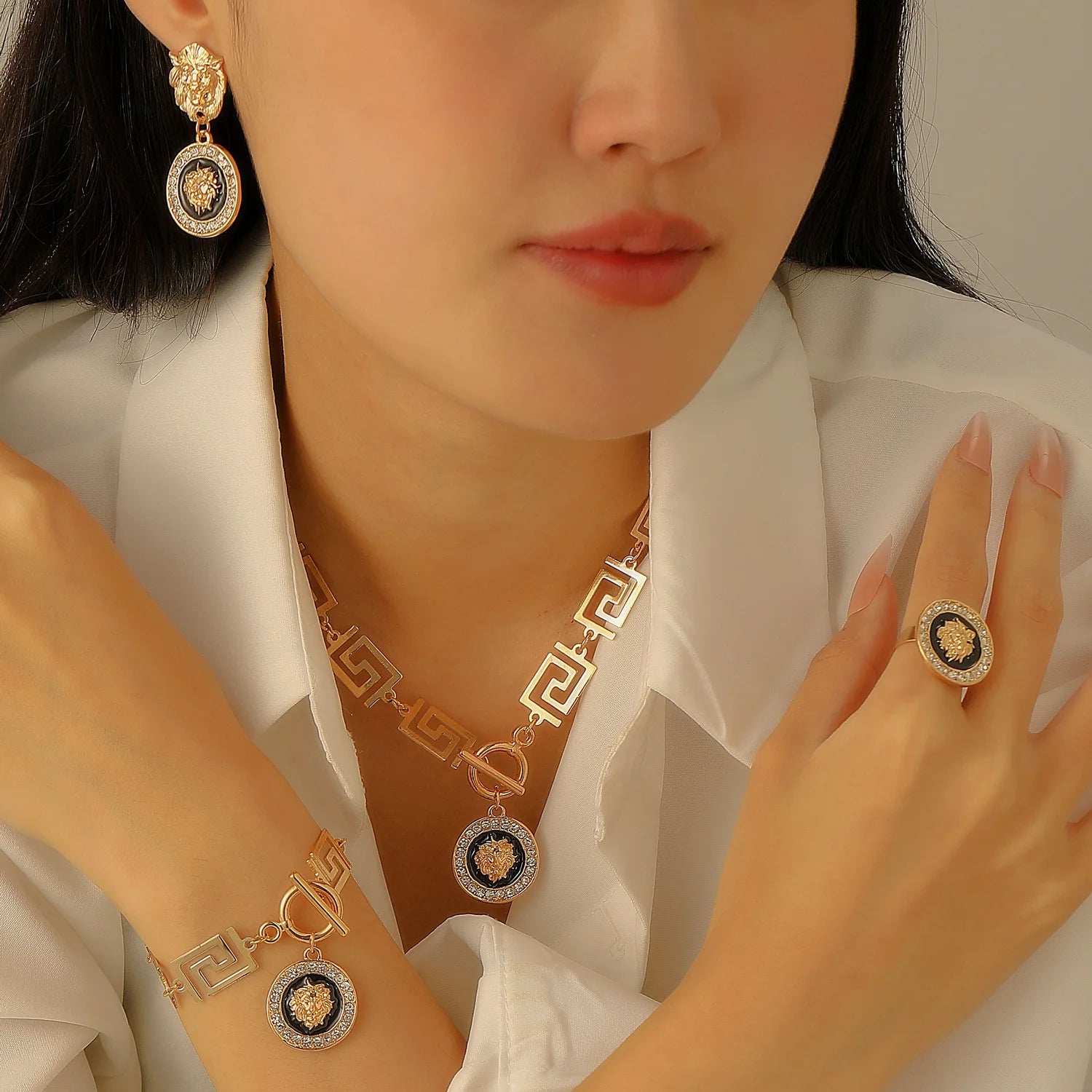 Close-up of a person wearing gold jewelry with intricate designs on a neutral background