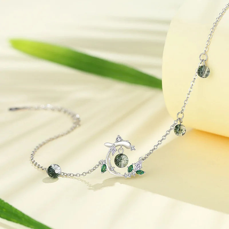 Silver bracelet with green gemstones on a light background
