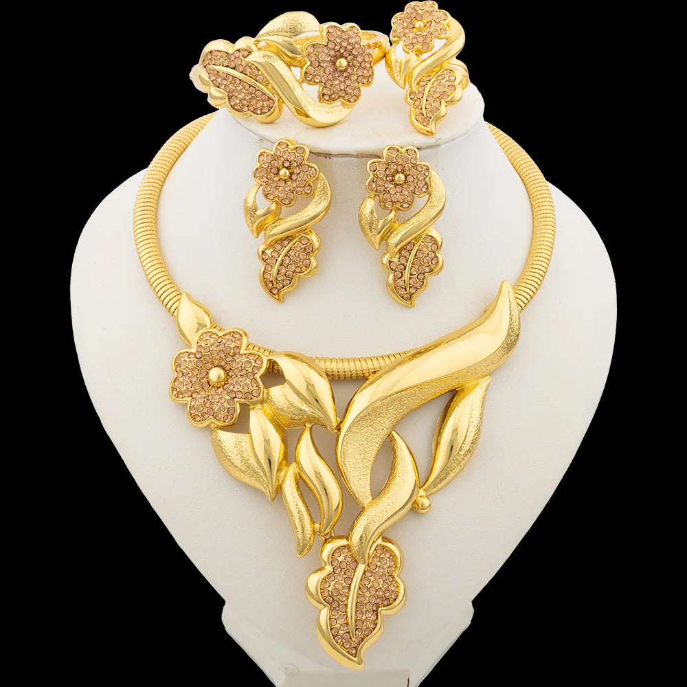 Gold necklace and earrings set on a white stand with a black background