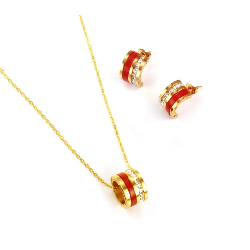 Jewelry set with gold necklaces and green and red accents on a white background