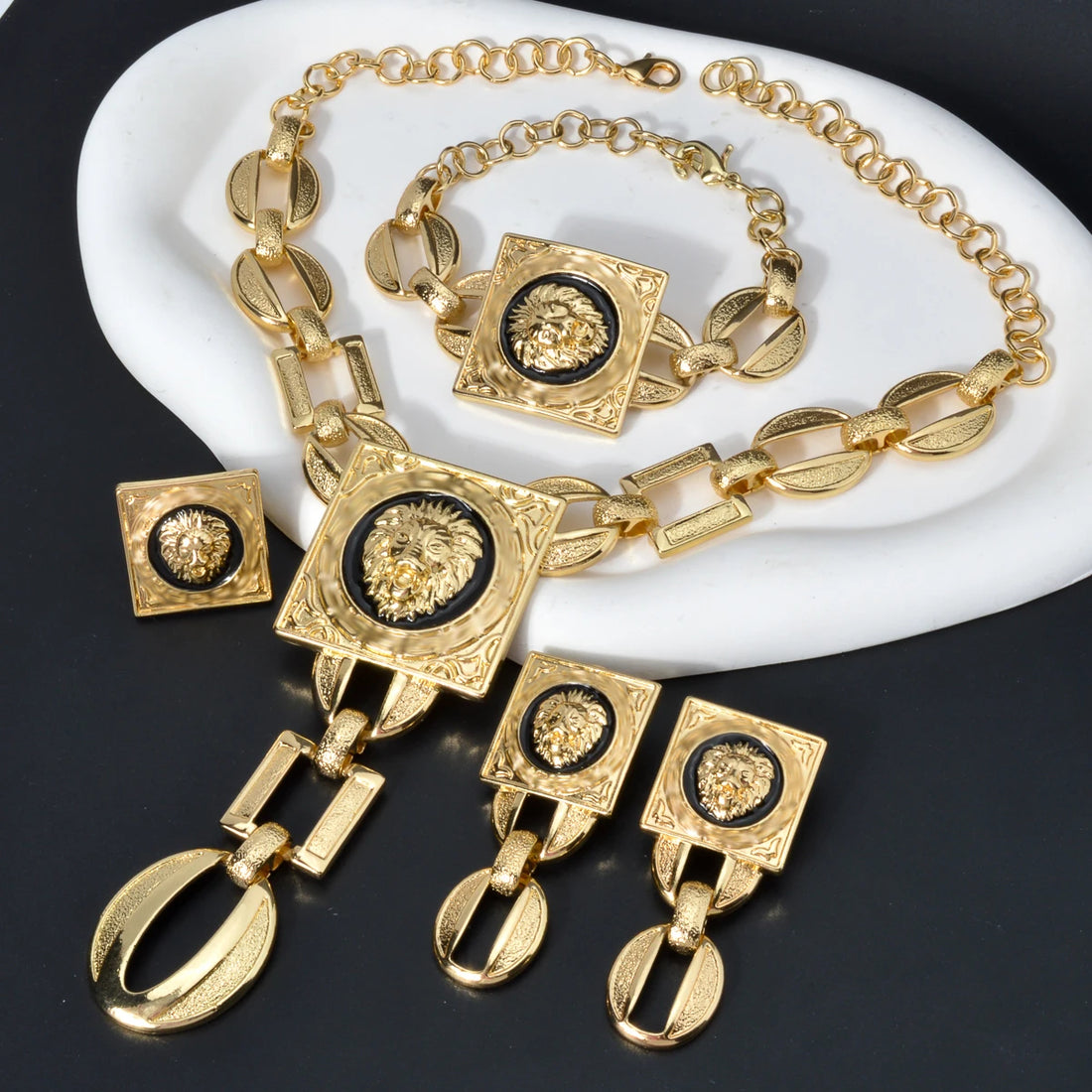 Gold necklace and earrings set on a black stand with a gray background