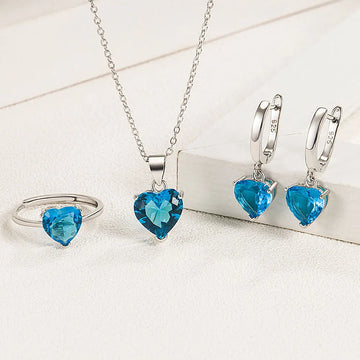 Silver jewelry set with blue heart-shaped gemstones on a white surface