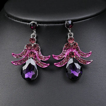Pink and purple earrings with gemstones on a dark background