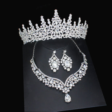 Silver tiara, necklace, and earrings set on a black background