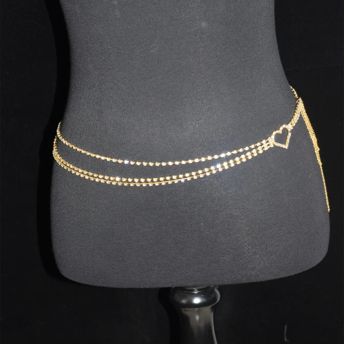 Gold chain necklace worn by a person with black pants and a white background